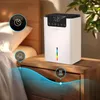 A white humidifier sits on a wooden nightstand next to a bed. Náhled obrázku produktu