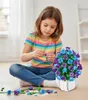A young girl is sitting on the floor, assembling a bouquet of artificial flowers. Náhľad obrázku produktu