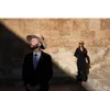 Two people stand in front of a stone wall, one in the foreground and one in the background. Voir les images du produit