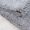 A close-up view of a gray shaggy rug, showing its texture and the underside where it is folded. Produktbild-Vorschau