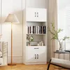 A white tall cabinet with shelves and doors, filled with books and decorative items, stands in a well-lit room next to a floor lamp and a window with sheer curtains. Produktbild-Vorschau