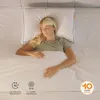 A woman sleeping peacefully on a bed with a white pillow and white bedding. Produktbild-Vorschau
