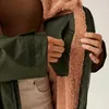 Close-up of a person's hands showing the inside of a green jacket with a brown fuzzy lining. Produktbild-Vorschau