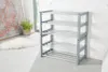A grey shoe rack with multiple shelves is shown in a room with a white brick wall and a light-colored floor. Produktbild-Vorschau