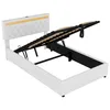 A white upholstered bed frame with the mattress support mechanism lifted to reveal storage space underneath. Náhled obrázku produktu