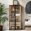 A tall, narrow cabinet with glass doors and LED lighting, displaying various bathroom or personal care items. A large potted plant is to the left, and a round mirror and sink are visible to the right. Anteprima dell’immagine prodotto
