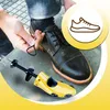 A person is shown lacing a black dress shoe while a yellow shoe stretcher is inserted into it. A circular graphic with a shoe outline is in the upper right corner. Podgląd zdjęcia produktu
