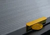 A close-up shot of two gold-colored decorative elements placed on a dark surface with a striped gray background. Anteprima dell’immagine prodotto