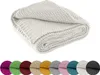 A folded white knitted blanket is shown against a white background. Below the blanket are circular swatches of various colors, likely representing other available colors for the product. Náhľad obrázku produktu