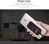 A hand holds a smartphone with a wireless charging receiver attached to the back, with a laptop and other items in the background. Náhľad obrázku produktu