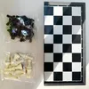 A chess set with pieces in plastic bags next to a chessboard. Produktbild-Vorschau