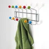 A colorful coat rack mounted on a white wall, with a green jacket hanging on it. Náhľad obrázku produktu
