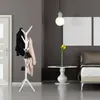 A modern entryway or bedroom setting with a white coat rack, a bed, and a side table. Produktbild-Vorschau