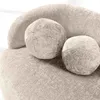 A close-up view of a textured beige sofa with two round decorative pillows. Produktbild-Vorschau