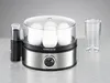 A silver and black egg cooker with white eggs inside, next to a clear plastic cup, on a gray surface with a light gray background. Produktbild-Vorschau