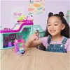A young girl is playing with a toy playset on a wooden table. Anteprima dell’immagine prodotto