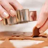 Hands using cookie cutters to cut shapes from gingerbread dough. Podgląd zdjęcia produktu