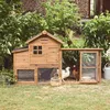 A wooden chicken coop with an attached run is set up in a grassy yard with lush green foliage in the background. Produktbild-Vorschau