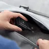 A hand is placing a black Samsung fast charger into a grey bag. Produktbild-Vorschau