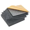 A stack of dark gray acoustic foam panels with one panel lifted to reveal the adhesive backing. Podgląd zdjęcia produktu