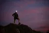 A person wearing a headlamp stands on a rocky outcrop against a twilight sky. Anteprima dell’immagine prodotto