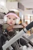A baby wearing earmuffs sits in a stroller. Anteprima dell’immagine prodotto