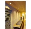 A modern hallway with wooden walls and ceiling, featuring a built-in shelf with a metallic kettle and a decorative plant. Produktbild-Vorschau