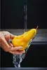 A hand holding a pear under running water in a sink. Náhľad obrázku produktu