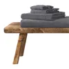 A stack of dark gray towels on a wooden bench. Produktbild-Vorschau