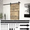 A sliding barn door with a black metal track and hardware, displayed in a room setting with a plant and artwork. Náhľad obrázku produktu