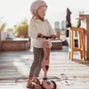 A young girl wearing a pink helmet rides a pink scooter on a wooden deck. Podgląd zdjęcia produktu