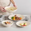 A person is presenting a bowl of soup, with other dishes of food and fruit salad on a table. Náhled obrázku produktu