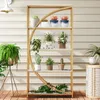 A multi-tiered shelf unit filled with various potted plants, displayed on a wooden deck against a light-colored, horizontally-paneled wall. Produktbild-Vorschau