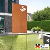 A rusty metal garden screen with butterfly cutouts stands in a grassy backyard next to a house and hedge. Produktbild-Vorschau
