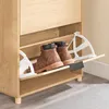 A pair of brown boots are placed inside a narrow shoe cabinet with a light wood finish. The cabinet has two pull-out drawers for shoes, each with a white plastic divider. Podgląd zdjęcia produktu