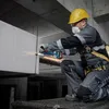 A construction worker is using an angle grinder to cut a metal rod in an unfinished building. Náhľad obrázku produktu