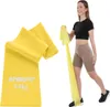A woman is using a yellow resistance band for exercise, with a folded resistance band shown in the foreground. Produktbild-Vorschau