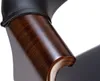 Close-up of a chair armrest, showing the wood grain and black leather. Podgląd zdjęcia produktu