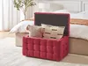 A red tufted storage ottoman is open and filled with two decorative pillows, placed in front of a bed in a bedroom setting. Náhled obrázku produktu