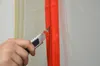 A hand is using a utility knife to cut along a red zipper. Produktbild-Vorschau