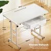A white adjustable desk with a drawer, shown in a room with wooden flooring and a plant. Podgląd zdjęcia produktu