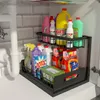A two-tier black metal organizer shelf filled with various cleaning supplies, positioned under a sink with plumbing visible. Produktbild-Vorschau