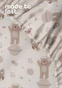 A close-up view of a baby bedsheet with a space-themed pattern featuring bears in astronaut suits, rockets, and planets. Produktbild-Vorschau