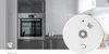 A smoke detector is shown in the foreground, with a kitchen scene in the background. Podgląd zdjęcia produktu