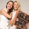 Two women smiling and holding a Christmas advent calendar. Produktbild-Vorschau