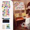 A young child is playing with a wooden easel that has a whiteboard and chalkboard, along with magnetic letters and numbers. Produktbild-Vorschau