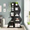 A black wavy bookshelf filled with decorative items like plants, books, and a camera, situated next to a gray sofa and a window. Podgląd zdjęcia produktu