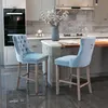 A modern kitchen with two light blue velvet bar stools.