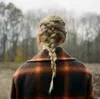 A person from behind wearing a plaid coat and a braided hairstyle, standing in an outdoor setting with trees in the background. Anteprima dell’immagine prodotto