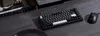 A black mechanical keyboard and mouse are placed on a dark gray wooden desk, with books and a stylus nearby. Produktbild-Vorschau